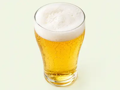 Verre de bière blonde dorée et pétillante surmonté d'un col de mousse blanche