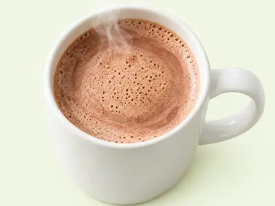 Mug blanc rempli de chocolat chaud mousseux et fumant