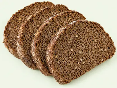 Quatre tranches de pain de seigle à la mie dense et brune, posées en éventail