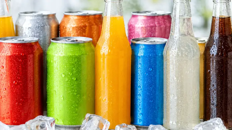 Canettes et bouteilles de sodas colorés posées sur de la glace