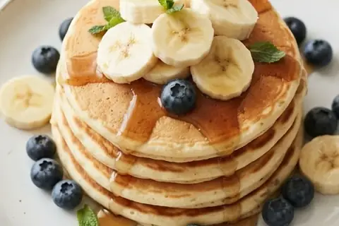 Pile de pancakes protéinés à la banane, aux myrtilles et au sirop