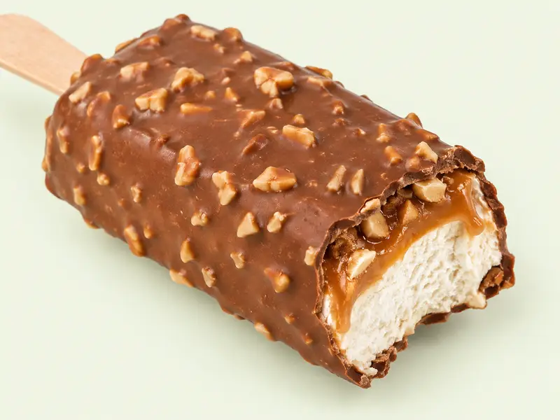 Barre glacée enrobée de chocolat et d'éclats de cacahuètes, croquée sur le côté, illustration du Snickers glacé